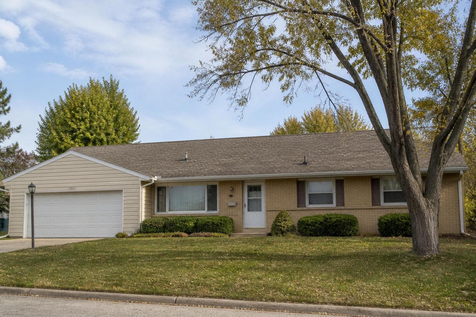One-story ranch house with a brown asphalt-shingle roof, brick front, and attached garage